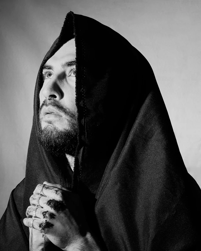 Black and white photograph of praying man wearing a tunic, looking towards the sky.