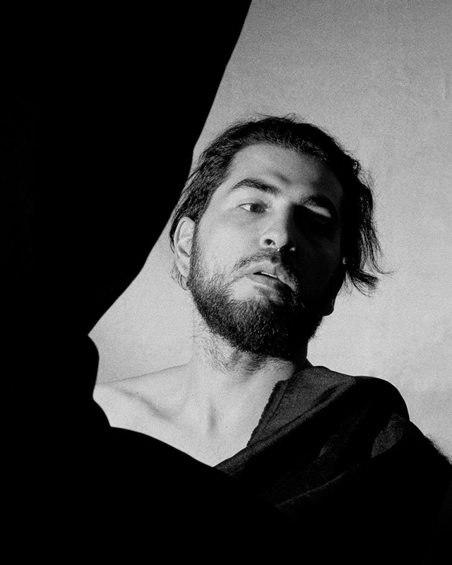 Black and white photograph of man behind canvases that are in the air.