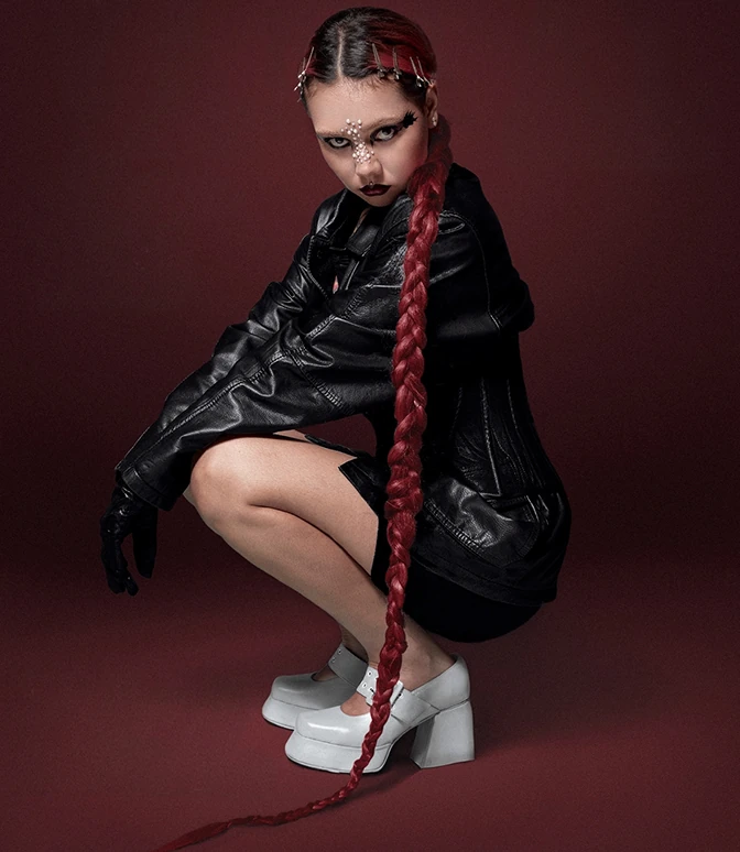 Fotografía editorial con fondo vinotinto y una mujer vestida con chaqueta de cuero