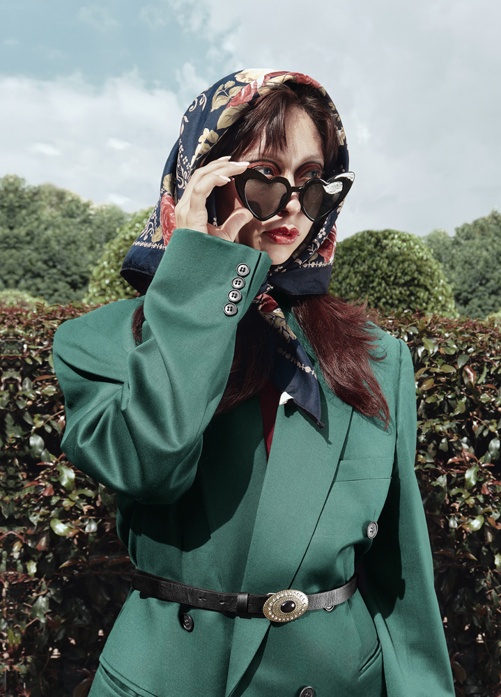 Portada editorial mujer con saco verde y gafas en forma de corazón, mirando al horizonte