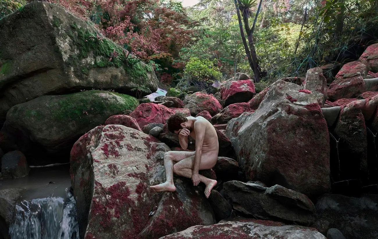 hombre setnado en medio de muchas rocas en medio de un bosque