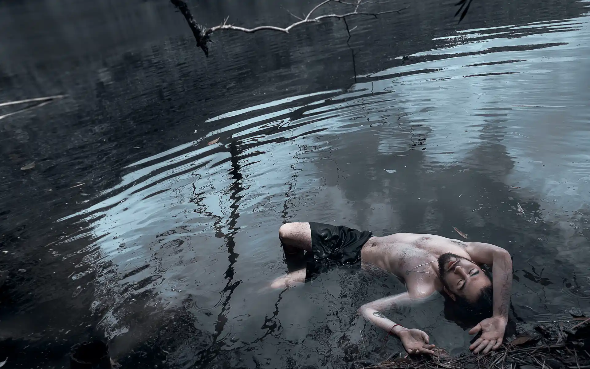 Hombre en medio de un lago, acostado con el torso descubierto