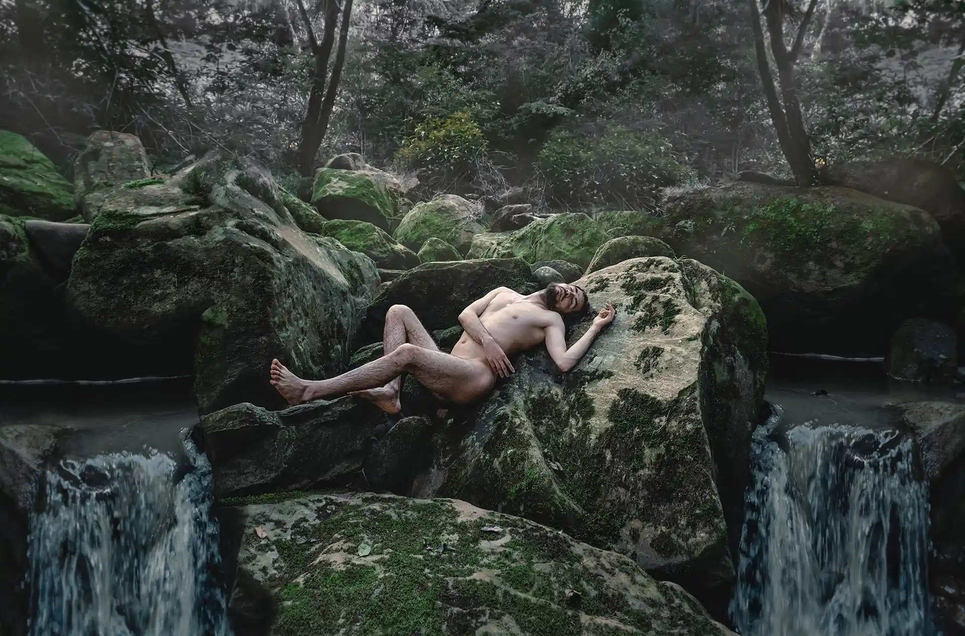 Hombre en medio de rocas de rio en medio de un bosque