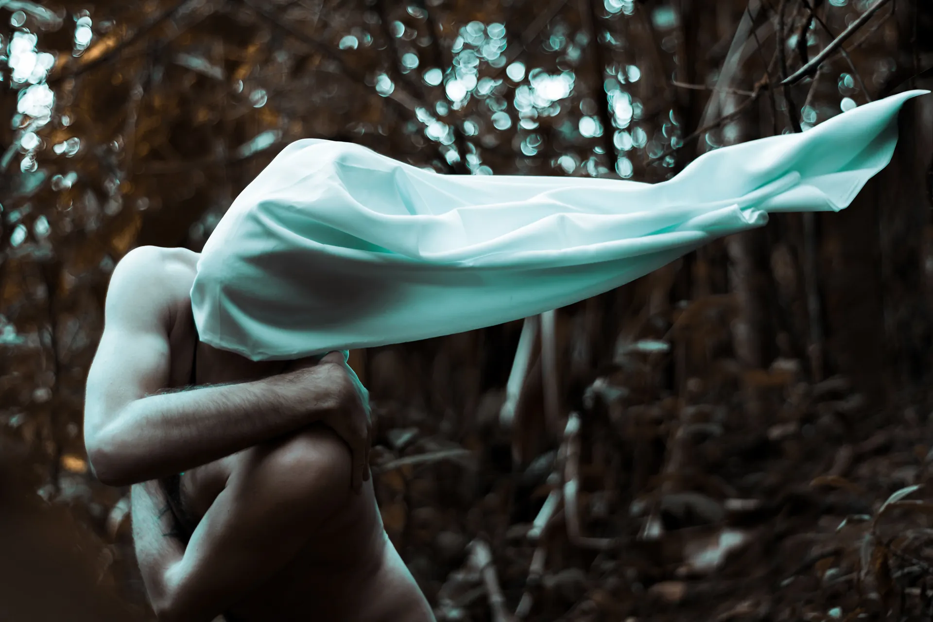 Hombre con una manta blanca en la cabeza en medio del bosque