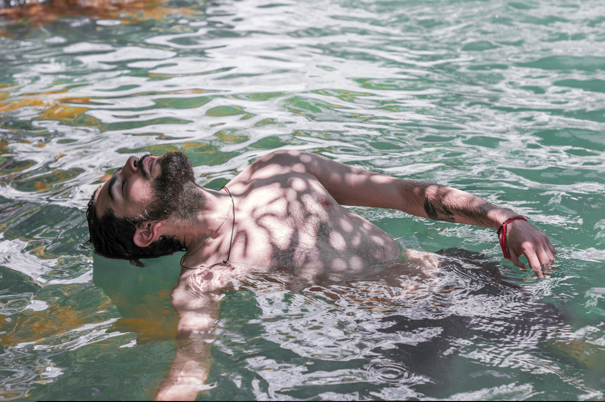 Artistic photograph of a man floating in the water of a lake.