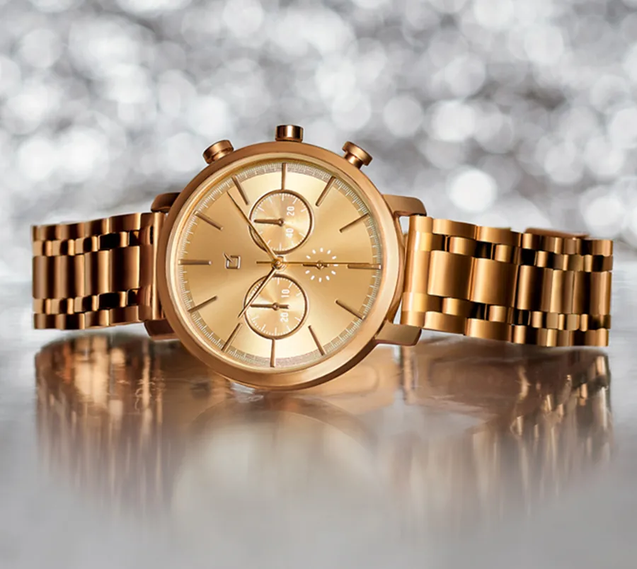 Photograph of a gold-colored watch on a silver background
