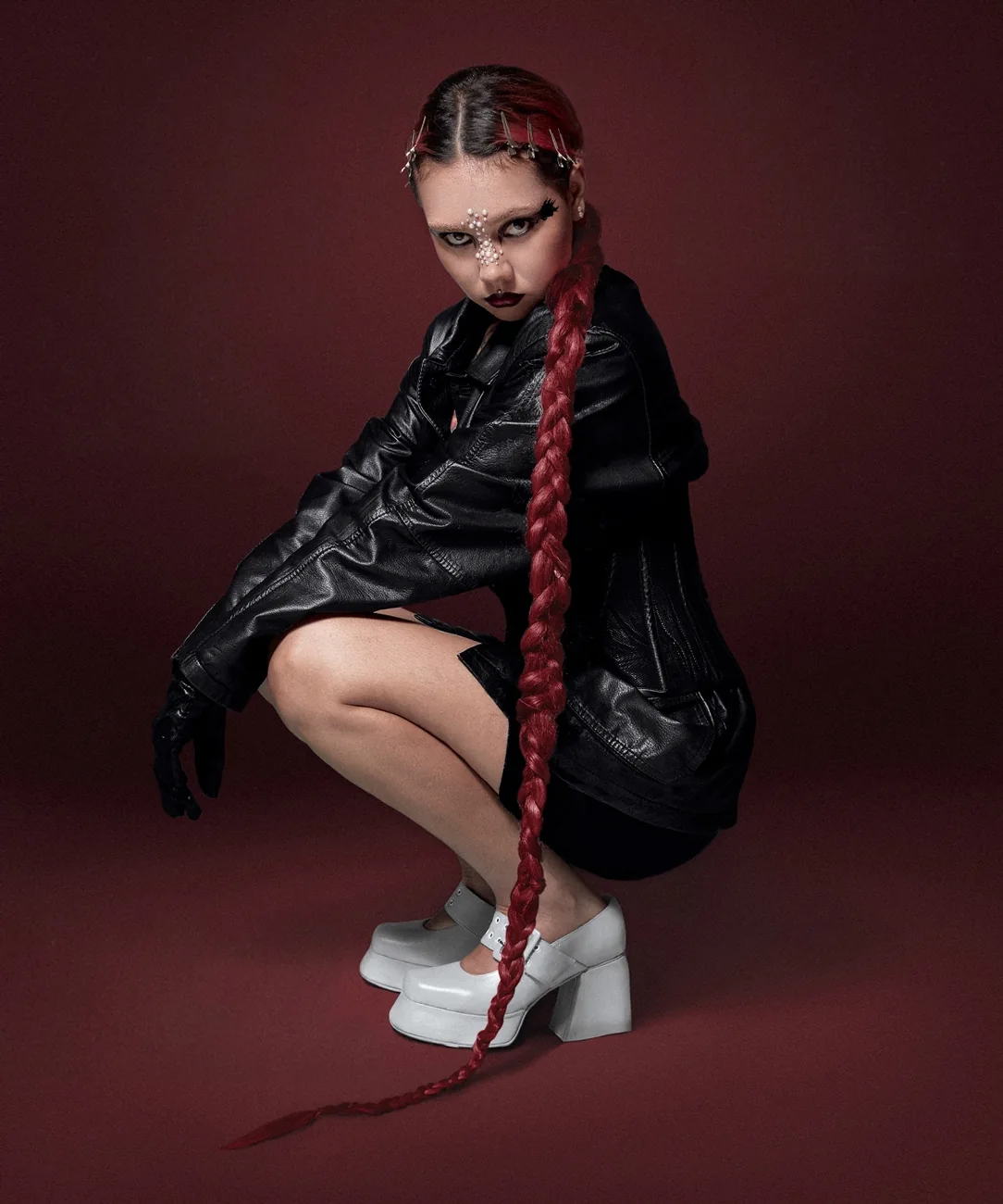 Fotografía editorial de una mujer arrodillada vestida de cahqueta de cuero y lleva una trenza hasta el suelo