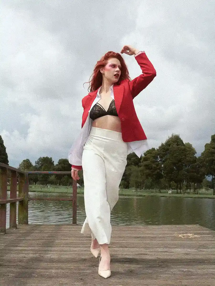 Fotografía editorial de una mujer caminanddo por un puente de madera y un lago detrás de ella