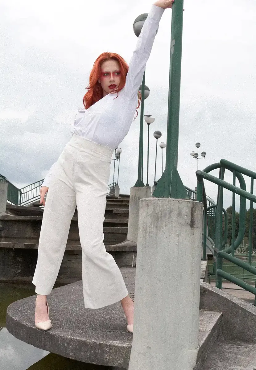 Fotografía de una mujer de pelo rojo posando al lado de una farola
