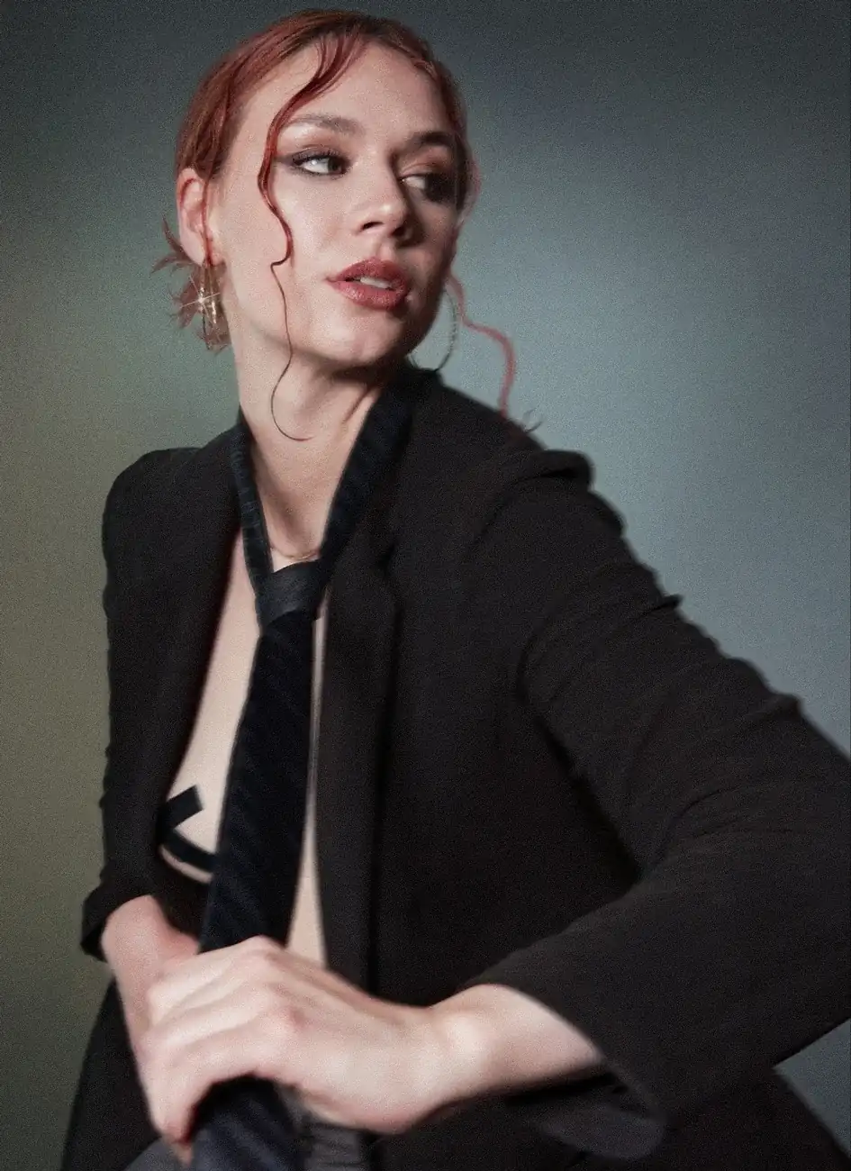 Fotografía de una mujer con un saco oscuro, estirando con su mano la corbata que esta en su cuello