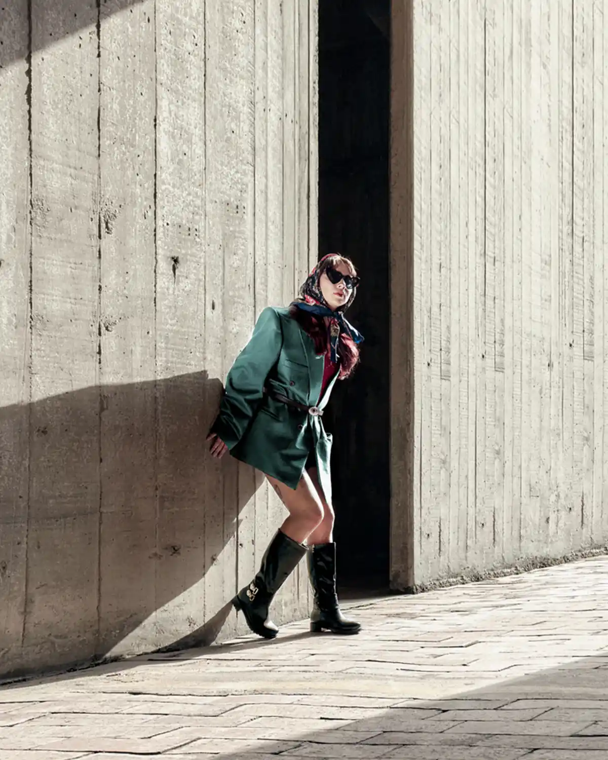 Fotografía editorial de una mujer con saco verde saliendo de una puerta