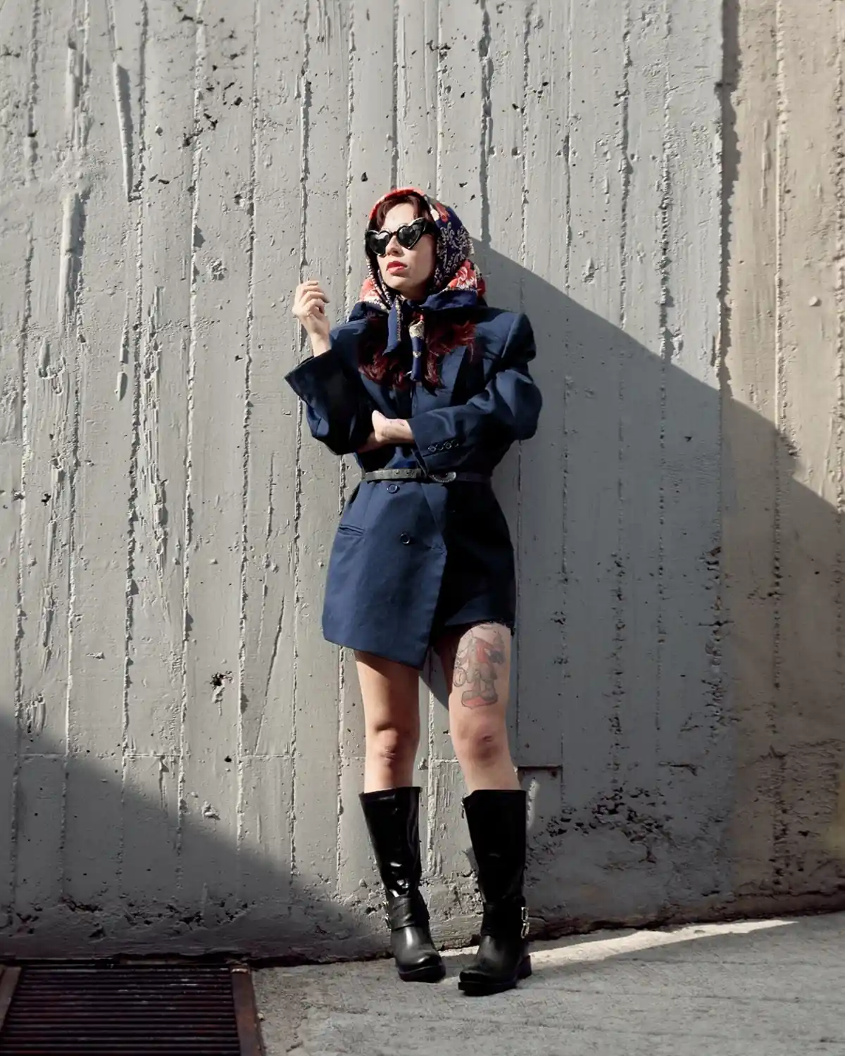 Fotografía editorial de una mujer con saco azul oscuro apoyada en una pared