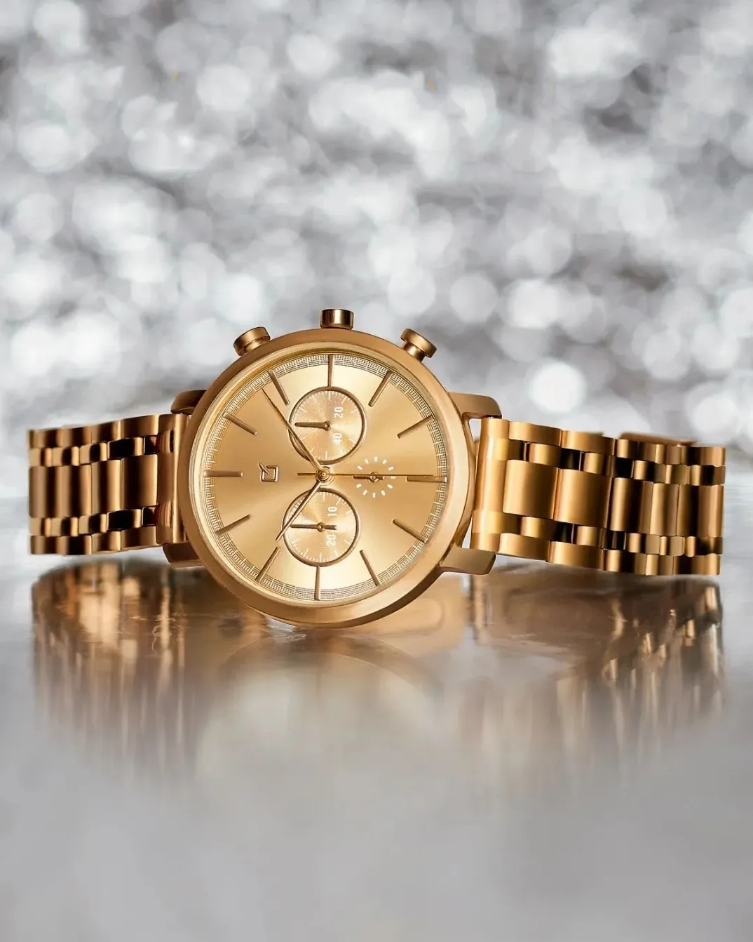 Fotografía de un reloj dorado, en un fondo plateado