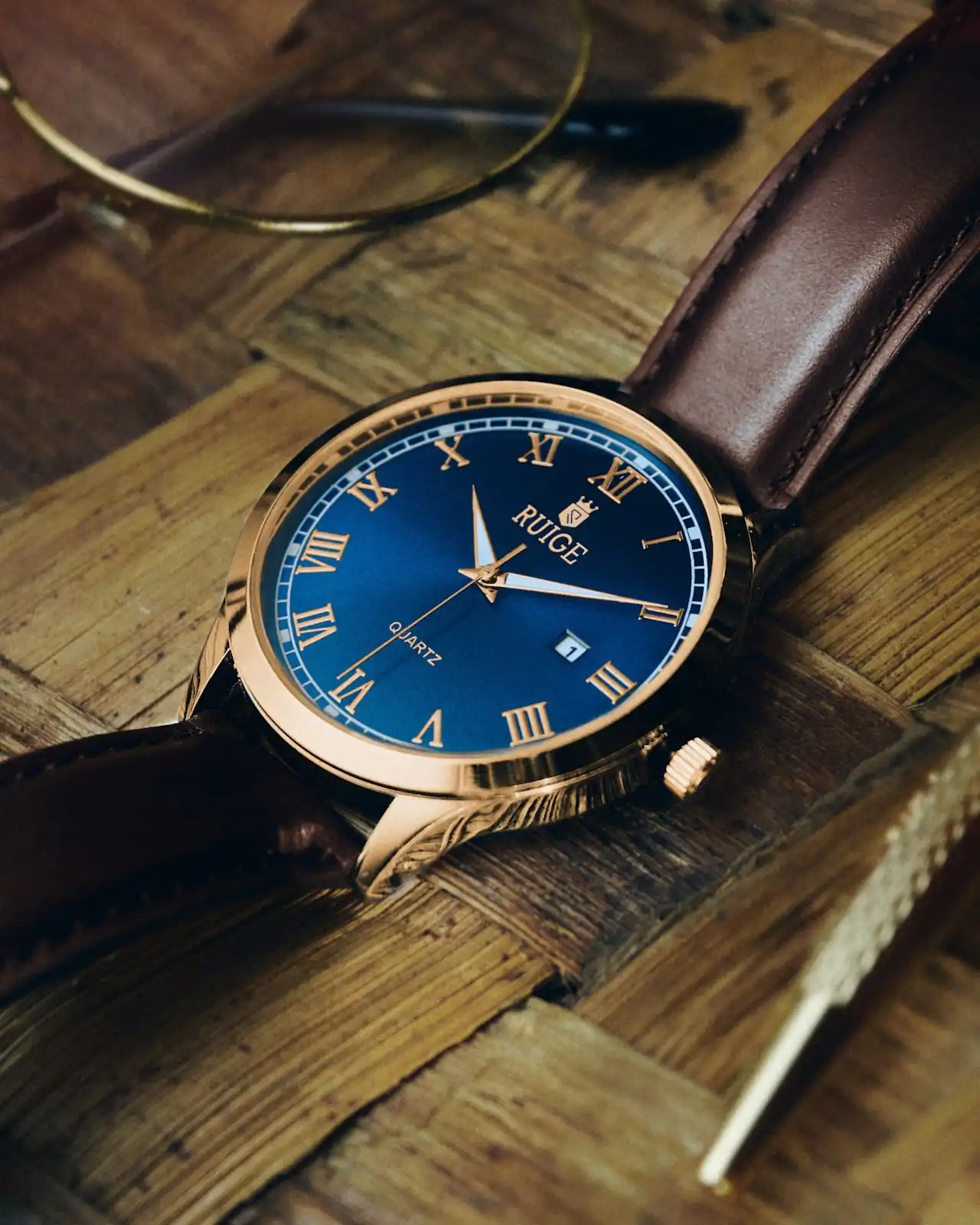 Fotografía de un reloj con esfera azul, correa de cuero marrón, y cuerpo dorado