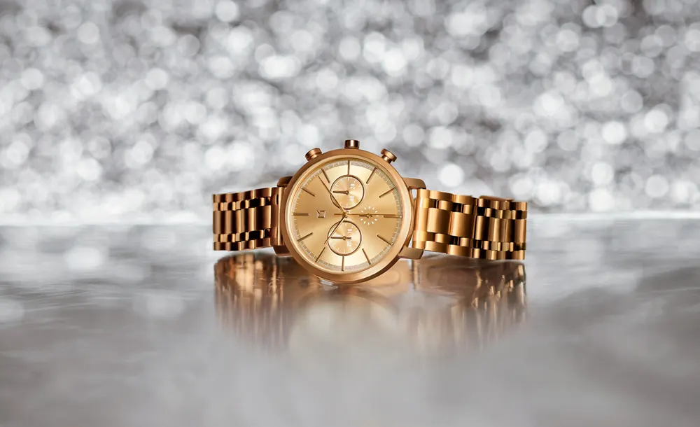 Fotografía de un reloj dorado, en un fondo plateado