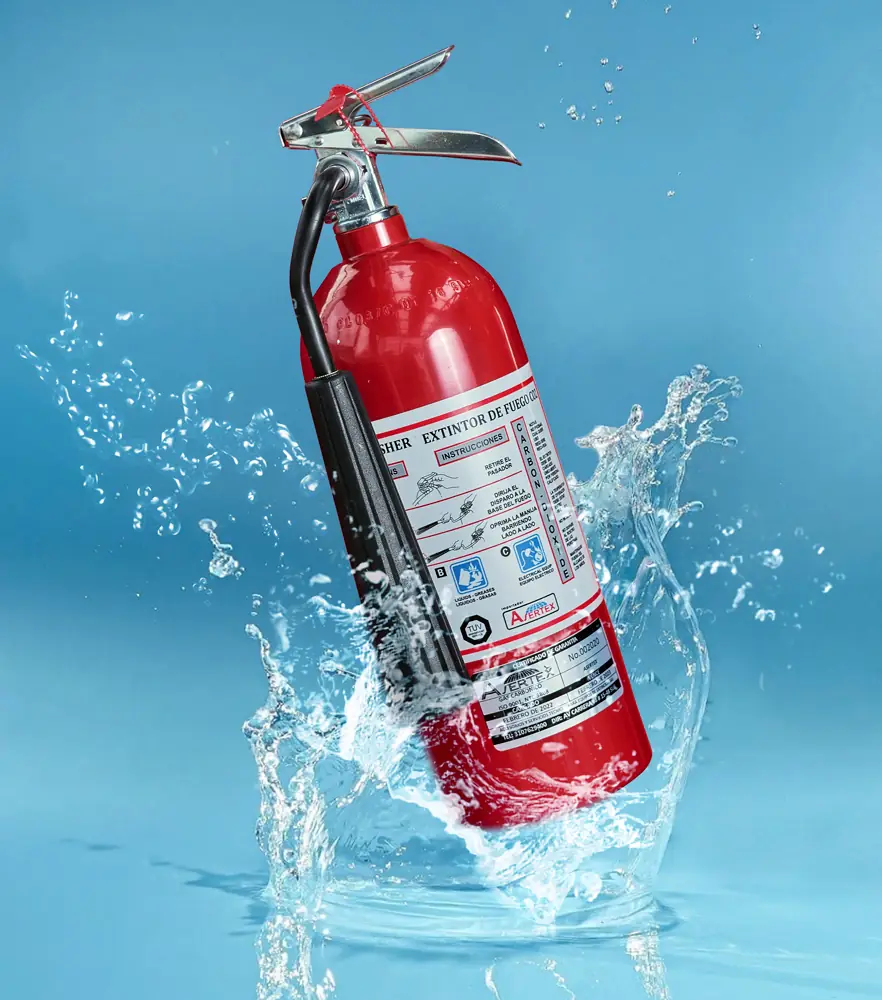 Fotografía de un extintor de color rojo salpicado por agua