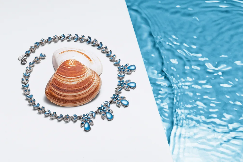 Fotografía de un collar con perlas azules, en un estanque de agua